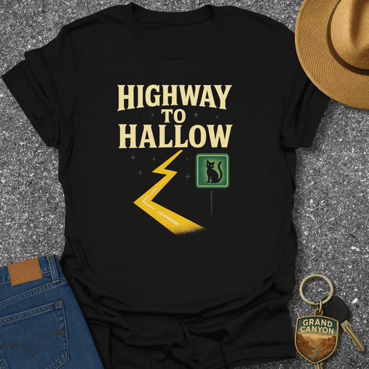 Black t-shirt with 'Highway to Hallow' design on a textured surface with jeans, hat, and keychain.