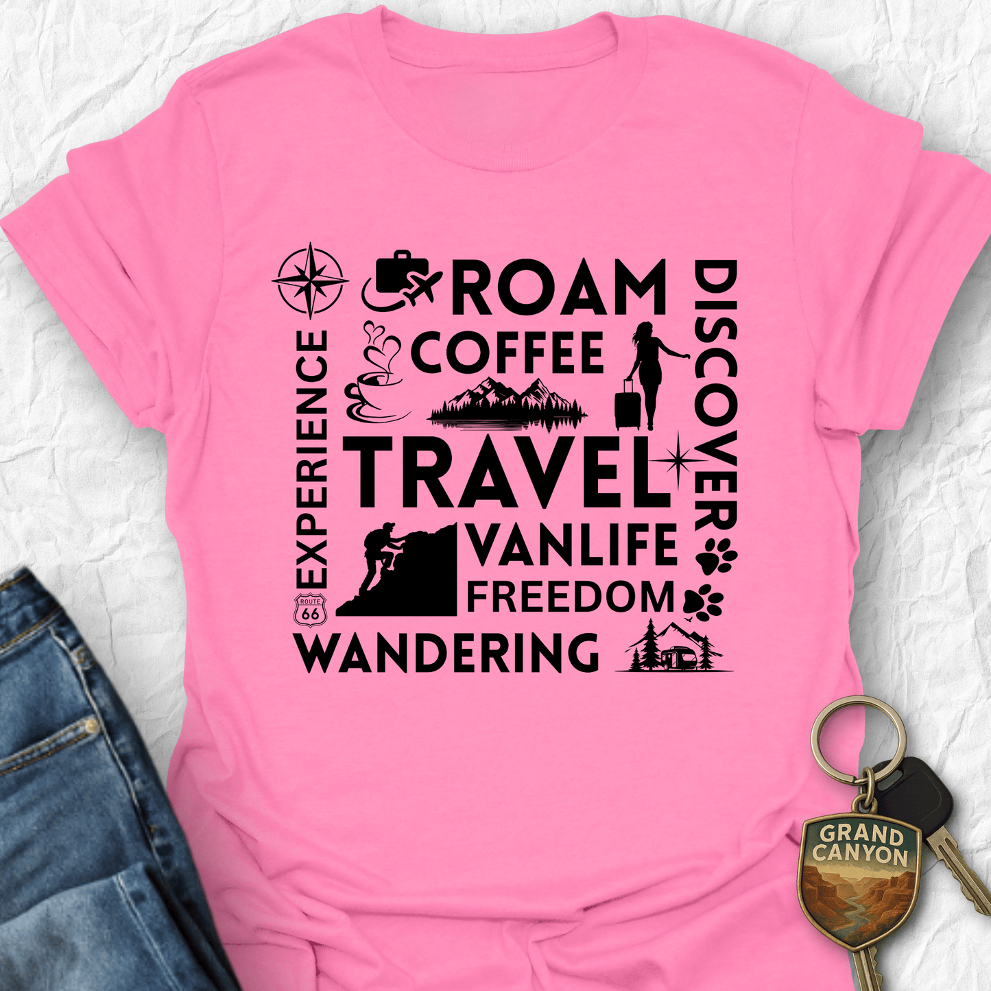 Pink t-shirt with black text and graphics on a textured surface with jeans and a keychain.