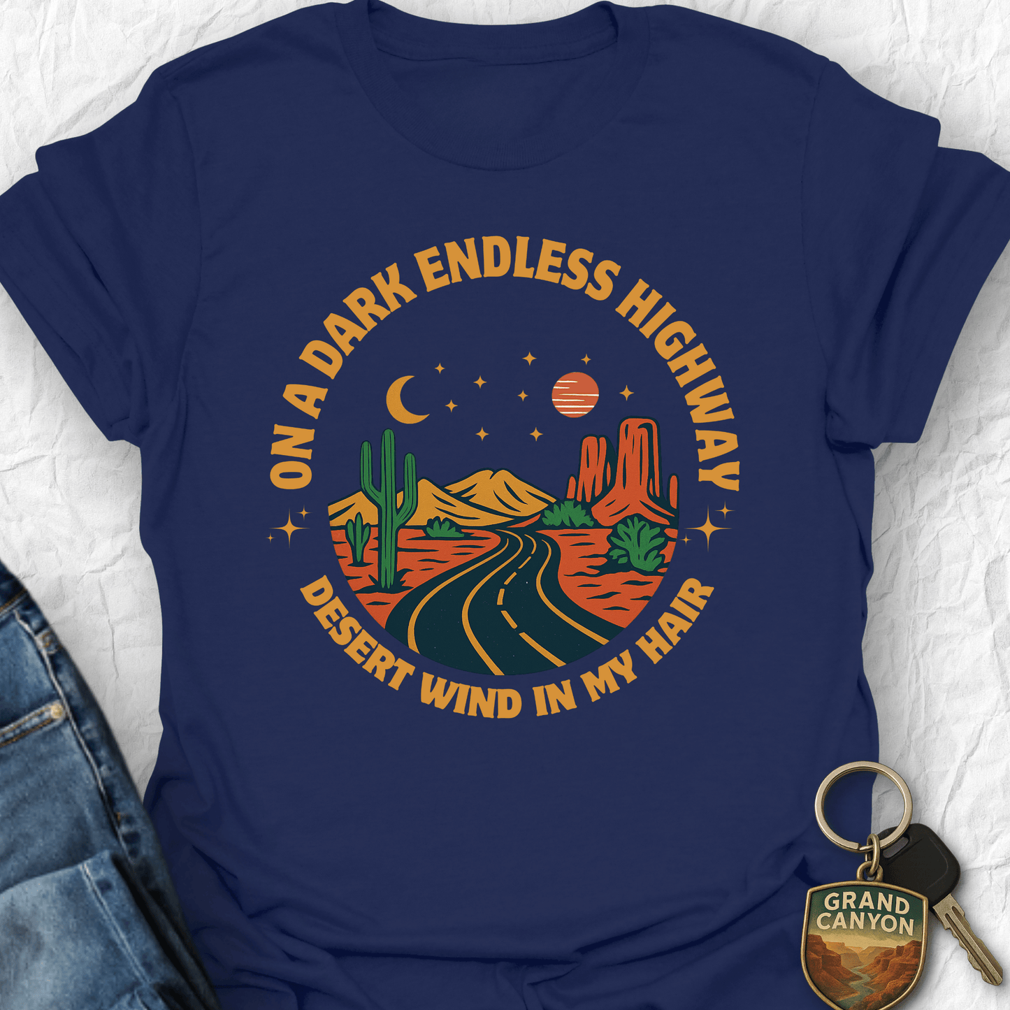 Navy blue t-shirt with desert-themed graphic and text on a textured white background