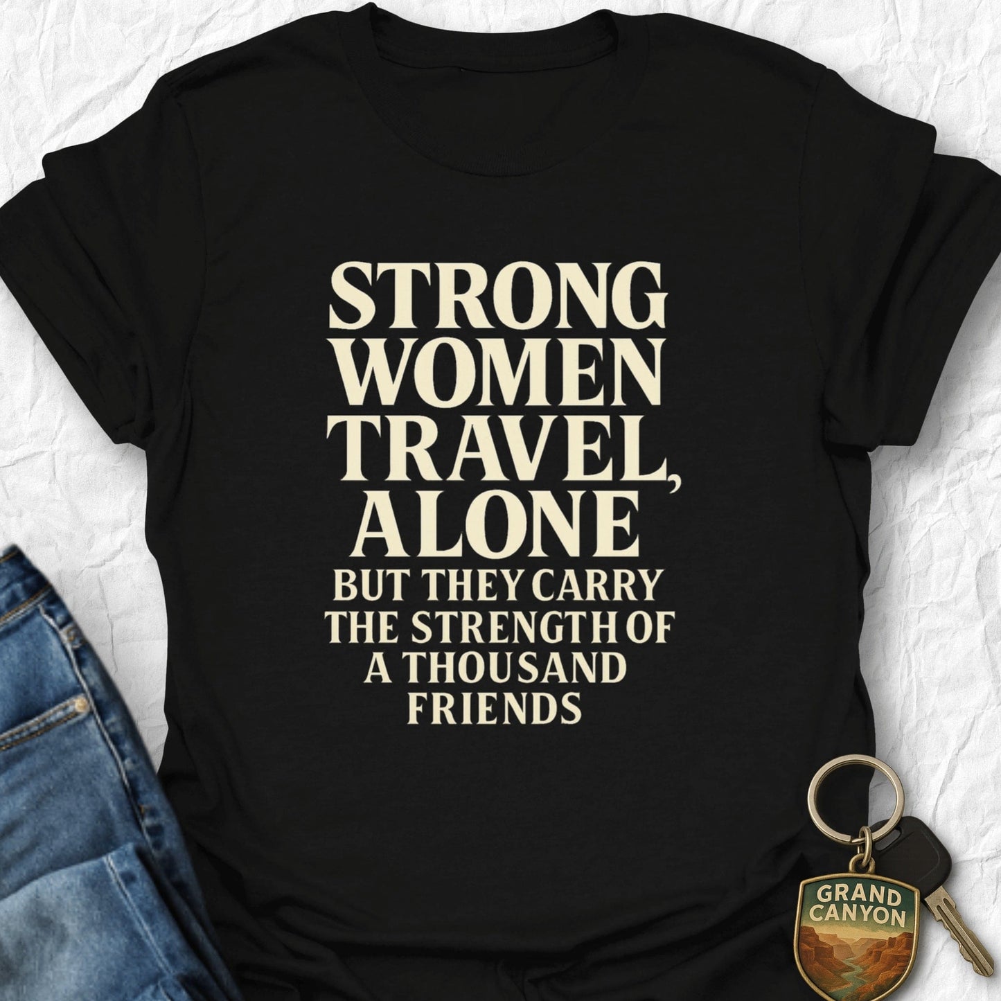 Black t-shirt with motivational quote on a textured surface with jeans and keychain.