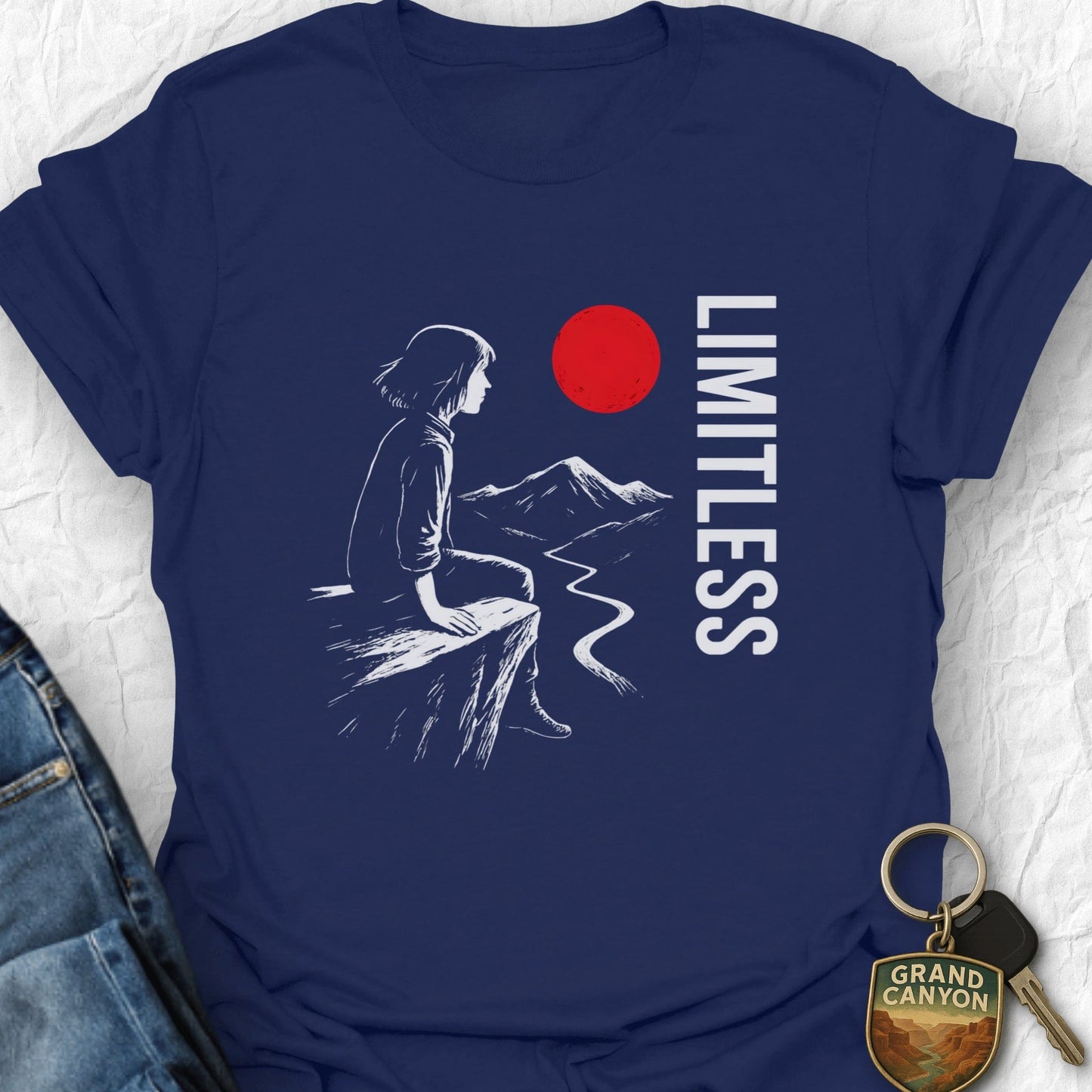 Navy blue t-shirt with a graphic of a person sitting on a rock, mountains, and a red circle with 'LIMITLESS' text.