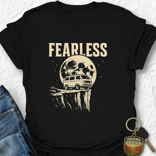 Black t-shirt with 'FEARLESS' graphic design featuring a van and moon, paired with jeans and a keychain on a textured white background.