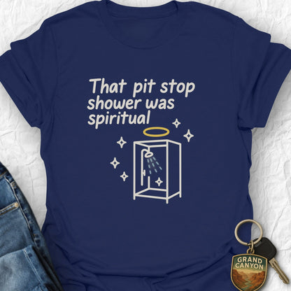 Navy blue t-shirt with humorous text and graphic, placed on a textured surface with jeans and keychain.
