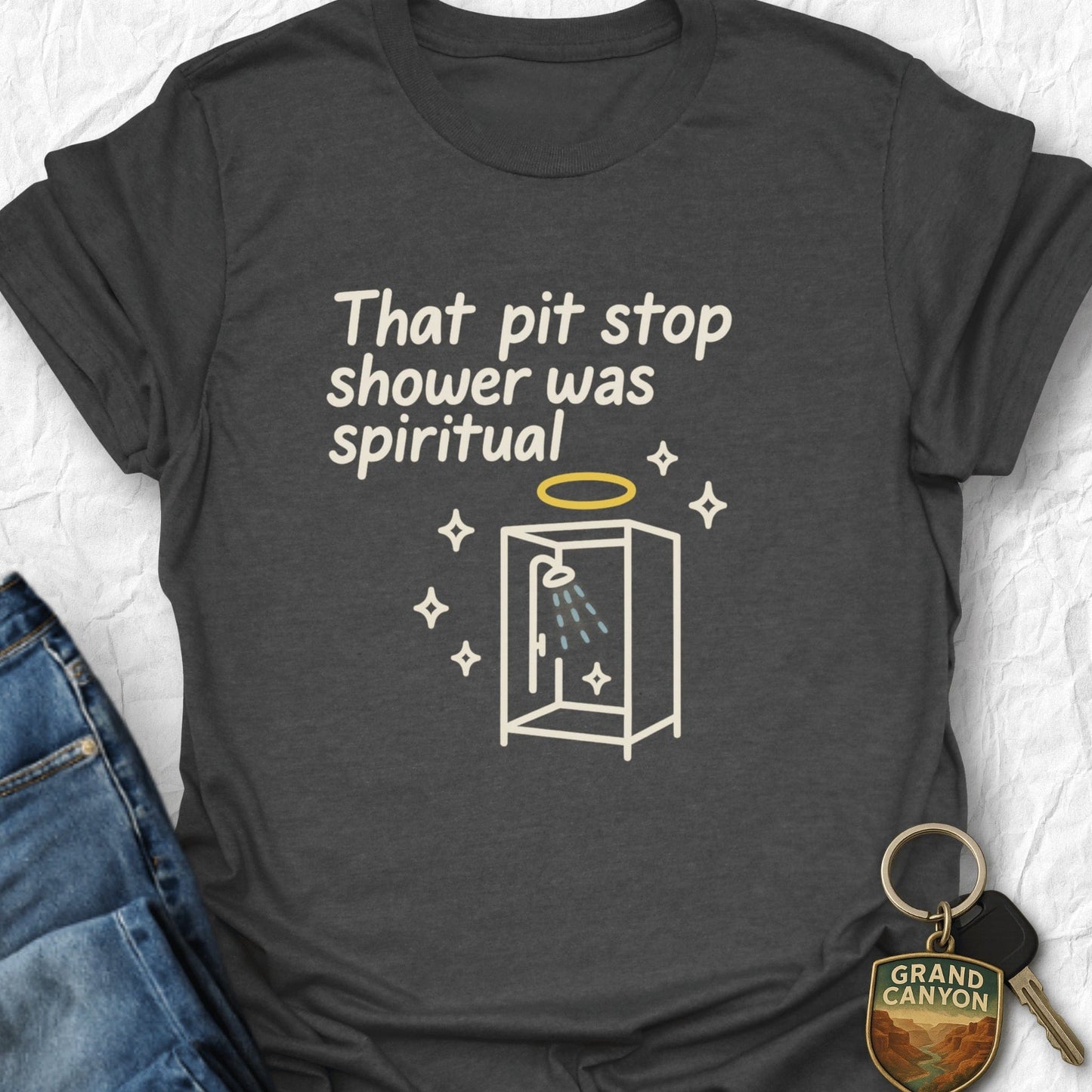 Dark gray t-shirt with humorous graphic and text, paired with jeans and a keychain.